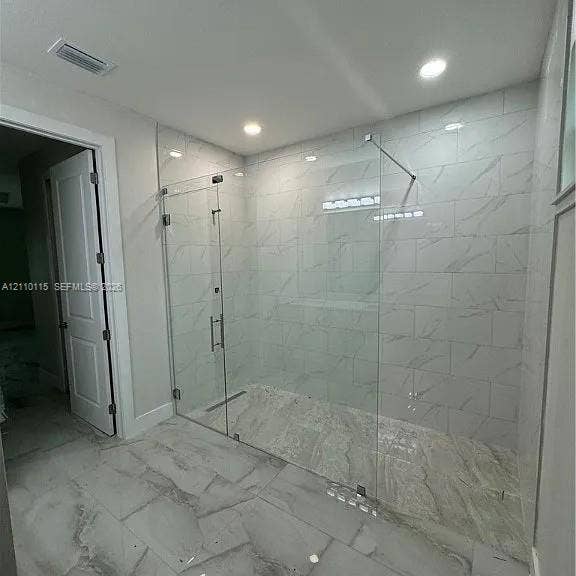 3304 11 Street W, #0, Lehigh Acres, FL 33971 Walk-in shower featuring a frameless glass enclosure, large-format tile wall surround, linear floor drain, and polished stone-finish floor tile