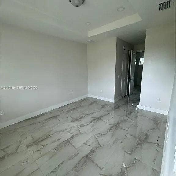3304 11 Street W, #0, Lehigh Acres, FL 33971 Interior room featuring large-format stone-finish tile flooring, recessed ceiling lighting, and a tray ceiling architectural detail