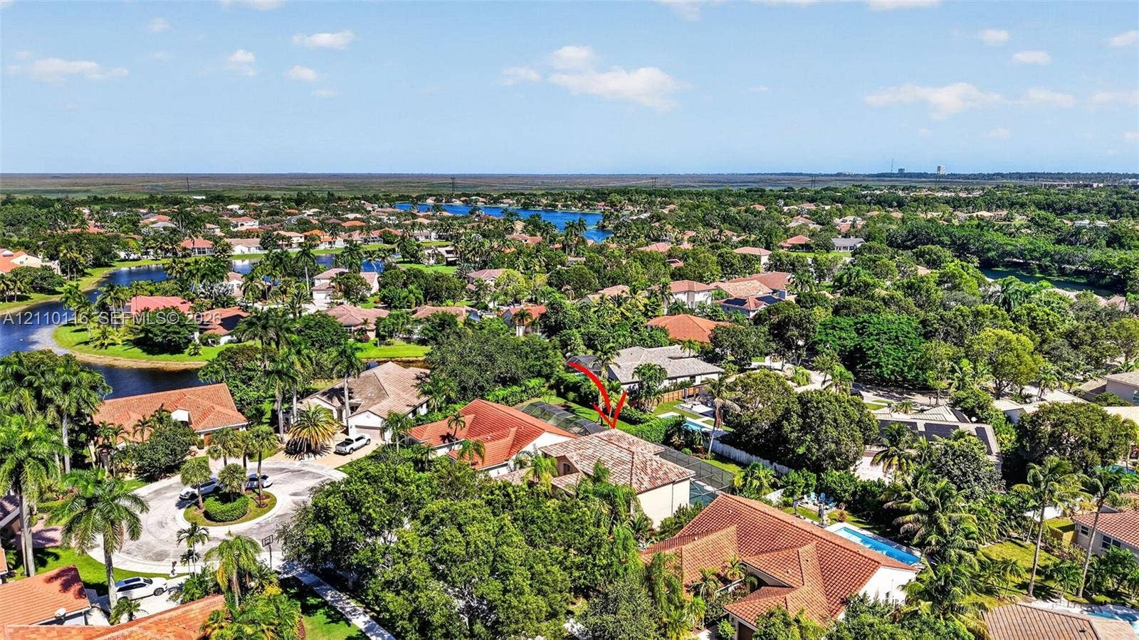 Aerial perspective of a multi-level residence featuring a multi-pitched tile roof and a screened-in rear enclosure