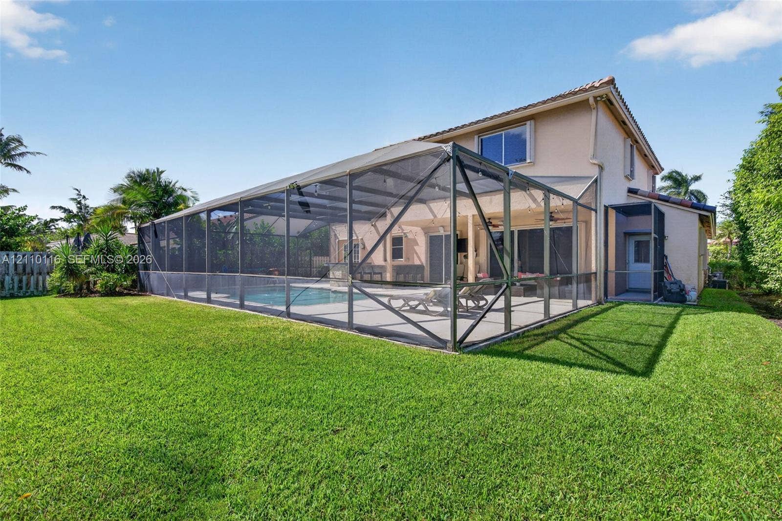 Screen-enclosed swimming pool featuring a concrete deck and a manicured lawn