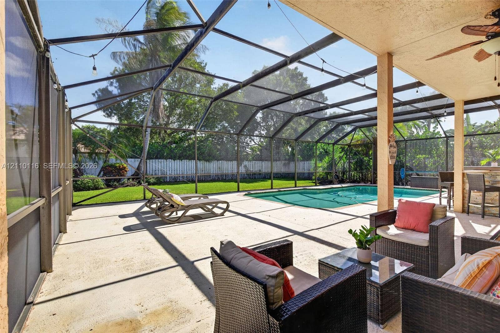 Screen-enclosed patio featuring a concrete deck, built-in outdoor bar, recessed ceiling fan, and swimming pool