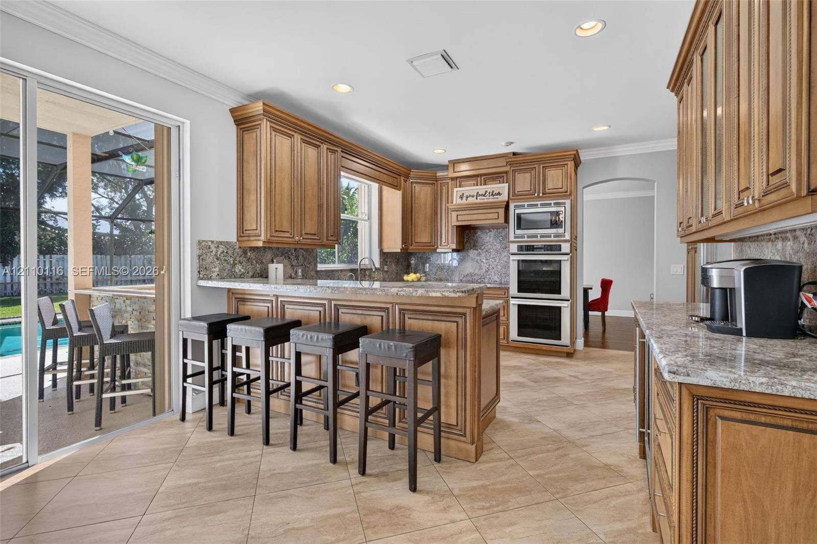 Kitchen featuring wood cabinetry, stone-surface countertops, tile flooring, recessed lighting, and built-in double wall ovens