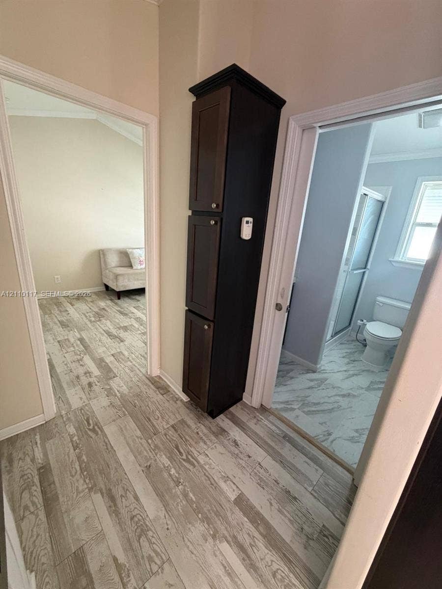 Tall, dark-stained wood-finish cabinetry featuring three tiers of storage, complemented by wood-finish flooring throughout