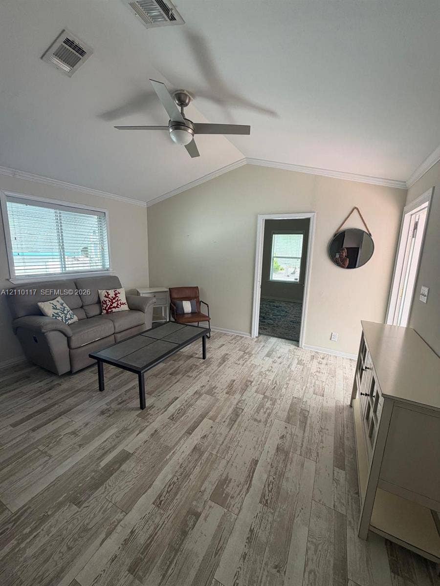 Vaulted ceiling featuring a ceiling fan and wood-finish flooring