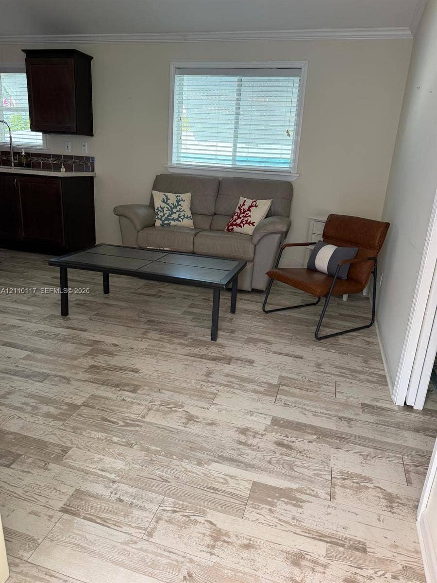 Wood-finish flooring throughout, dark-toned cabinetry, and horizontal window blinds