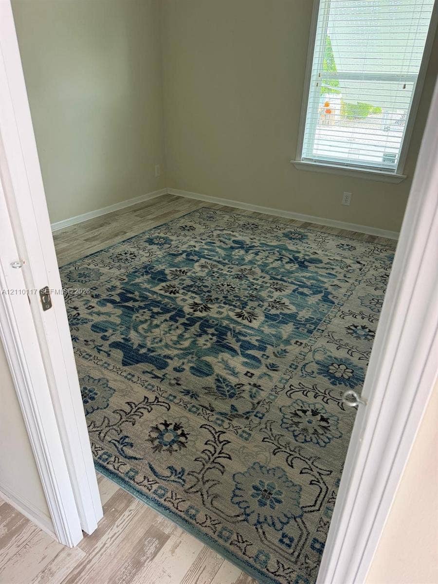 Room featuring wood-finish flooring and a window with horizontal blinds