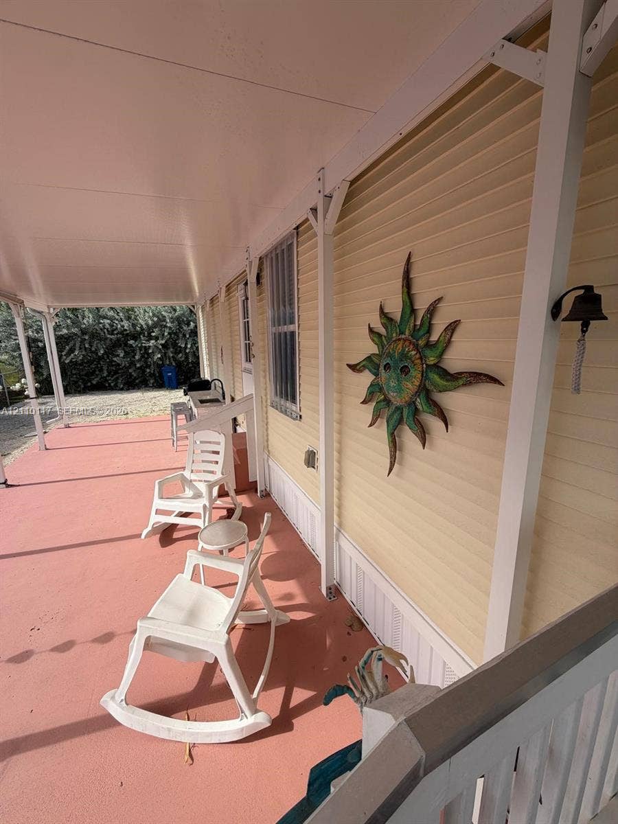 Covered porch featuring pale yellow horizontal siding, a solid-color painted deck, and an attached wall-mounted metal bell fixture