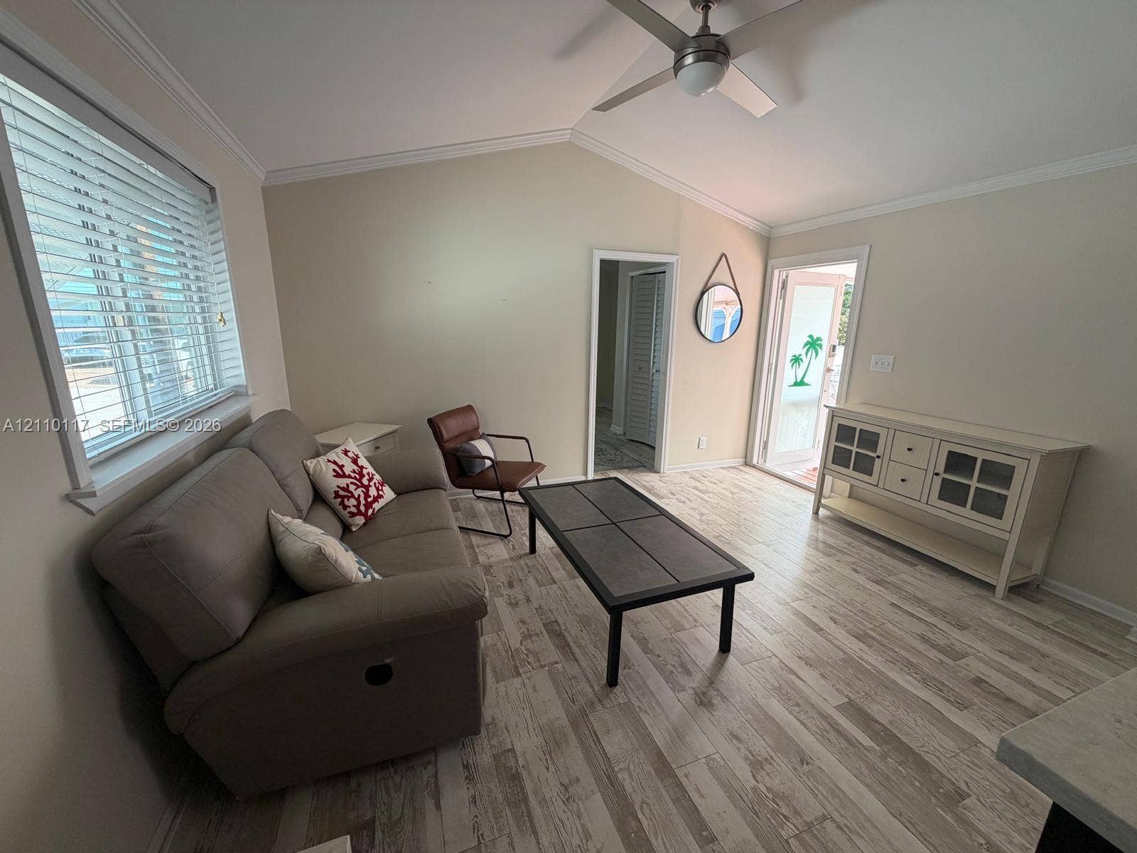 Vaulted ceiling featuring a central brushed-nickel ceiling fan, wood-finish tile flooring, and horizontal window blinds
