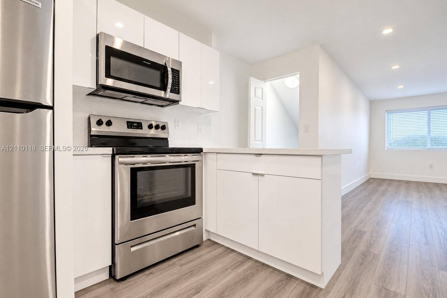 7991 SW 152nd Avenue, #701-7, Miami, Miami, FL 33193 Kitchen featuring white flat-panel cabinetry, stainless steel appliances, solid-surface countertops, and wood-finish flooring with recessed lighting