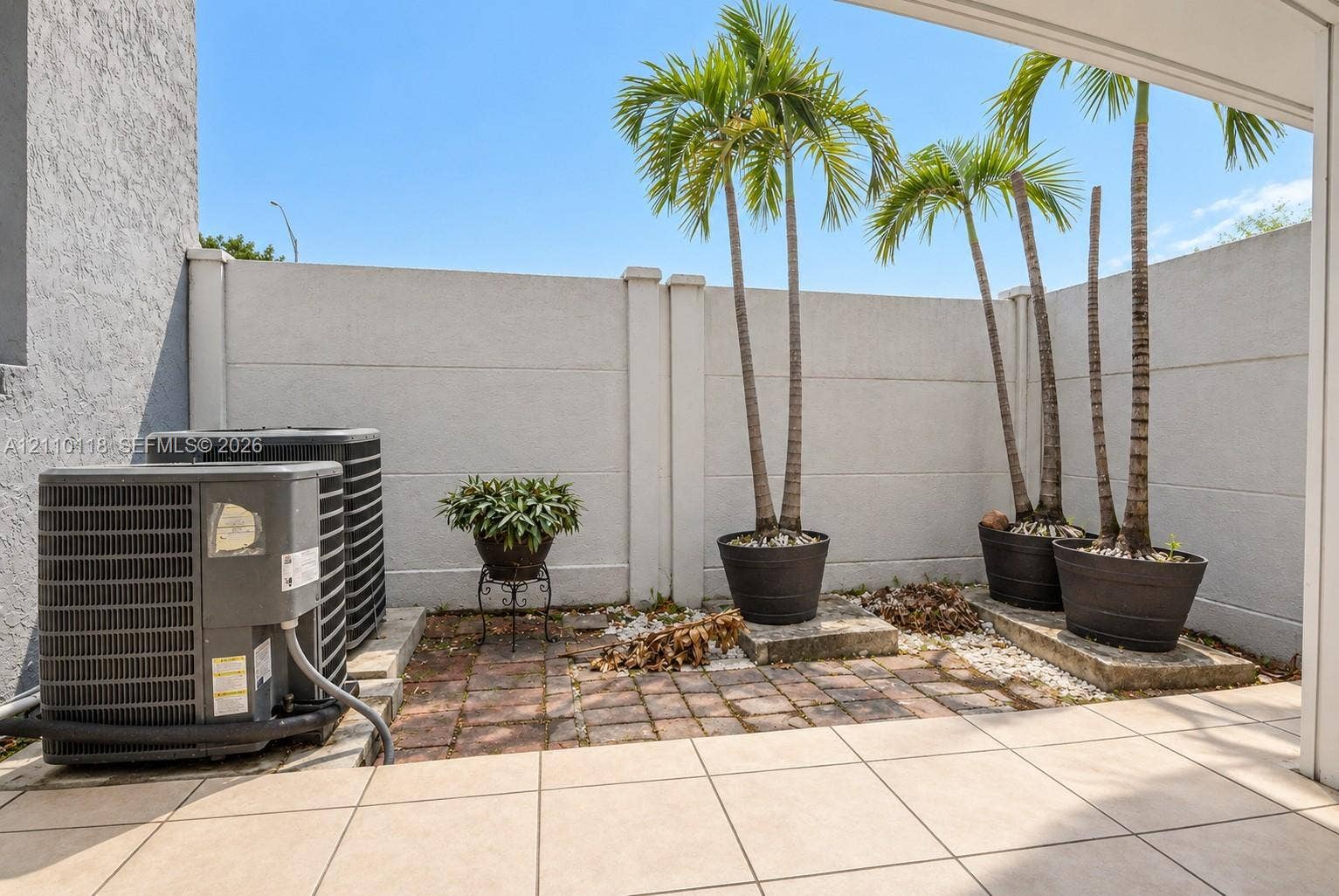 7991 SW 152nd Avenue, #701-7, Miami, Miami, FL 33193 Private outdoor patio featuring large-format tile flooring, a structured masonry privacy wall, and brick paver accents