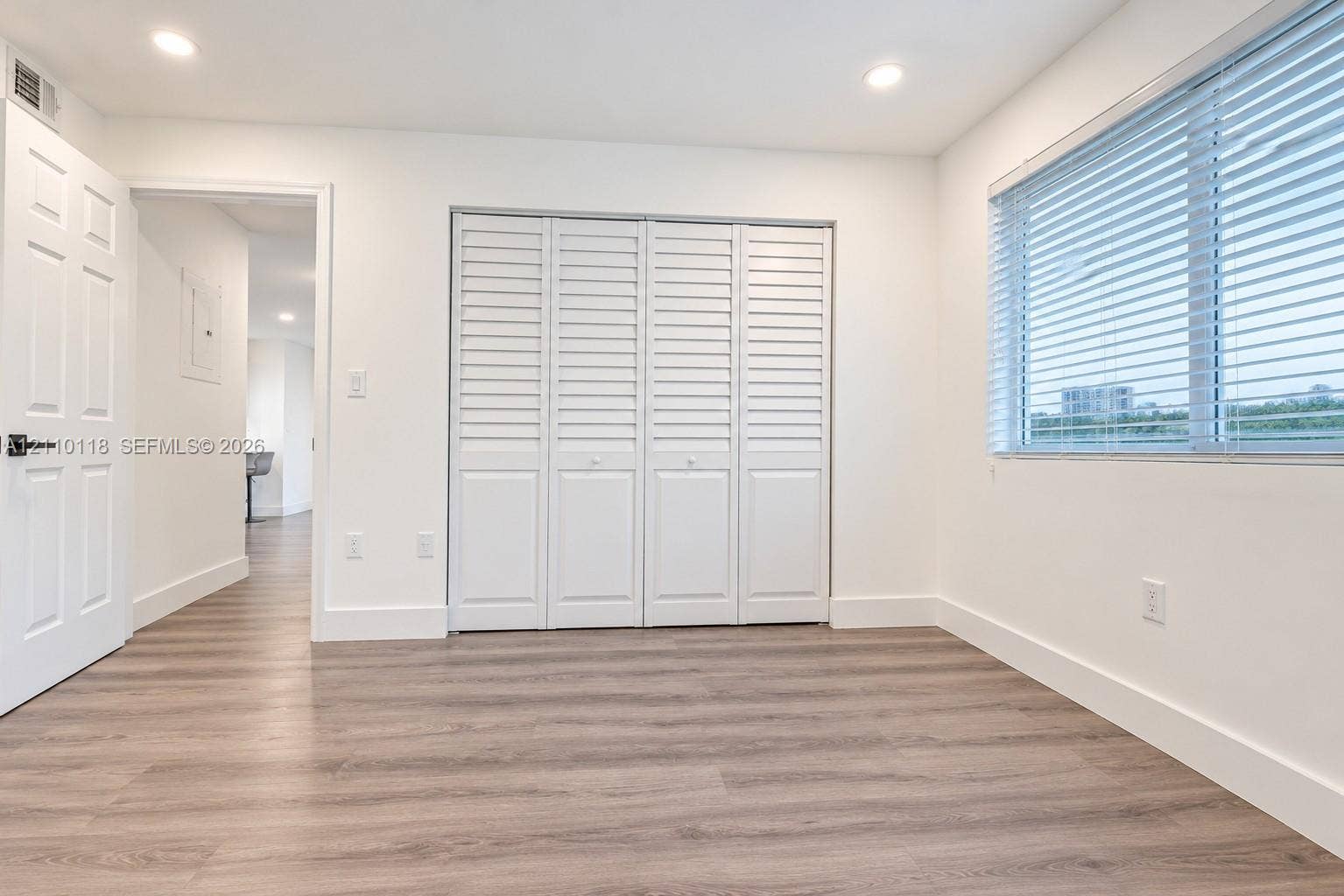 7991 SW 152nd Avenue, #701-7, Miami, Miami, FL 33193 Room featuring wood-finish flooring, recessed lighting, four-panel louvered closet doors, and a window with horizontal blinds
