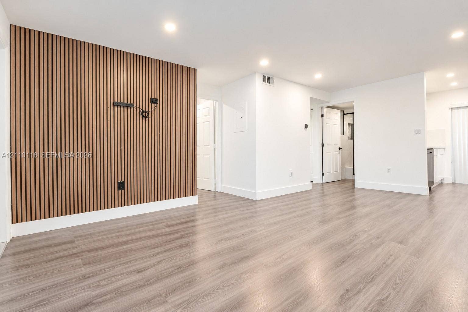 7991 SW 152nd Avenue, #701-7, Miami, Miami, FL 33193 Interior space featuring a vertical wood-slat accent wall, wood-finish flooring, recessed lighting, and multi-panel interior doors