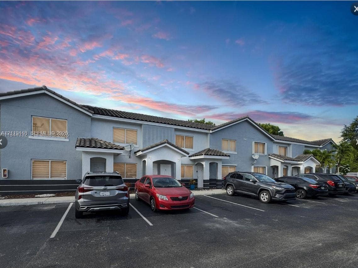 7991 SW 152nd Avenue, #701-7, Miami, Miami, FL 33193 Multi-family structure with stucco exterior, clay-tile roofline, covered entryway gables, and dedicated surface parking