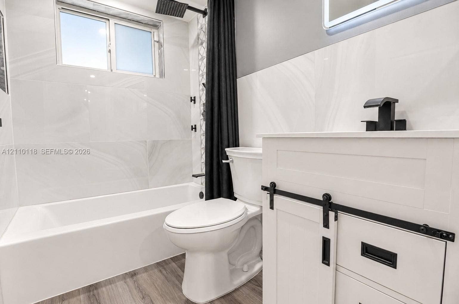 7991 SW 152nd Avenue, #701-7, Miami, Miami, FL 33193 Bathroom featuring large-format wall tile, wood-finish flooring, a white vanity with matte black hardware, and a rainfall showerhead