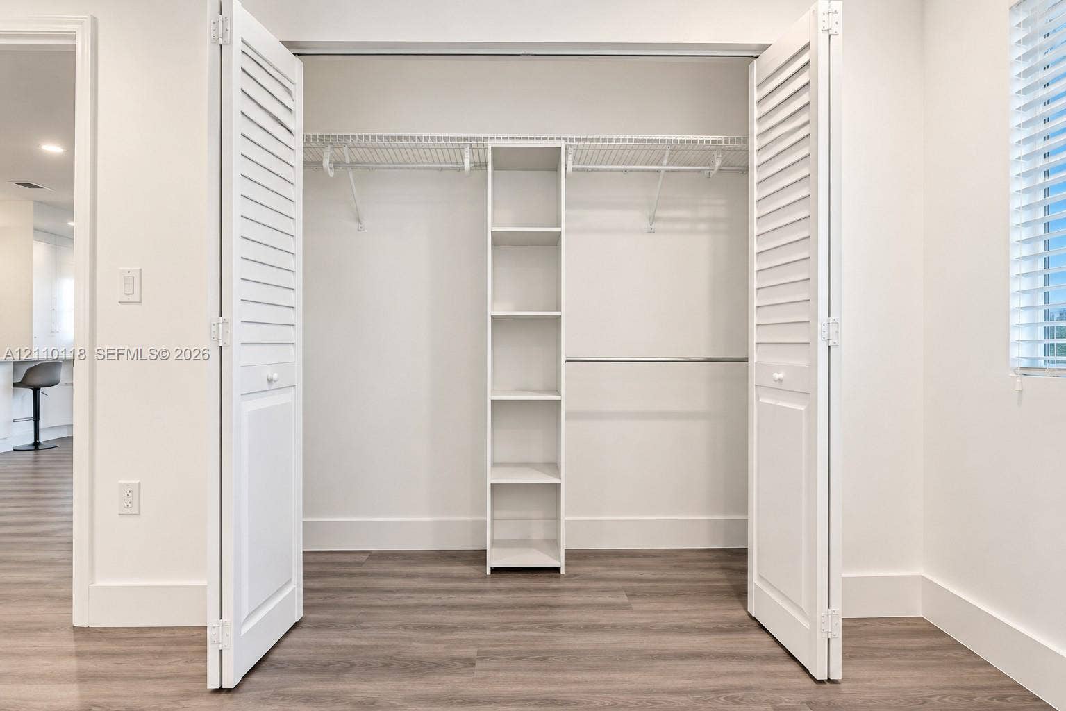 7991 SW 152nd Avenue, #701-7, Miami, Miami, FL 33193 Closet featuring louvered bifold doors, built-in shelving unit, dual wire racks, and wood-finish flooring
