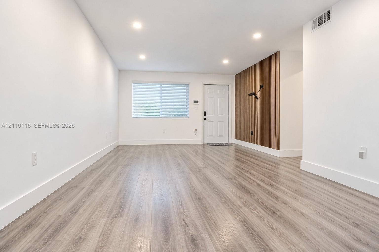 7991 SW 152nd Avenue, #701-7, Miami, Miami, FL 33193 Interior space featuring wood-finish flooring, recessed lighting, and a vertical wood-slat accent wall with a wall-mounted light fixture