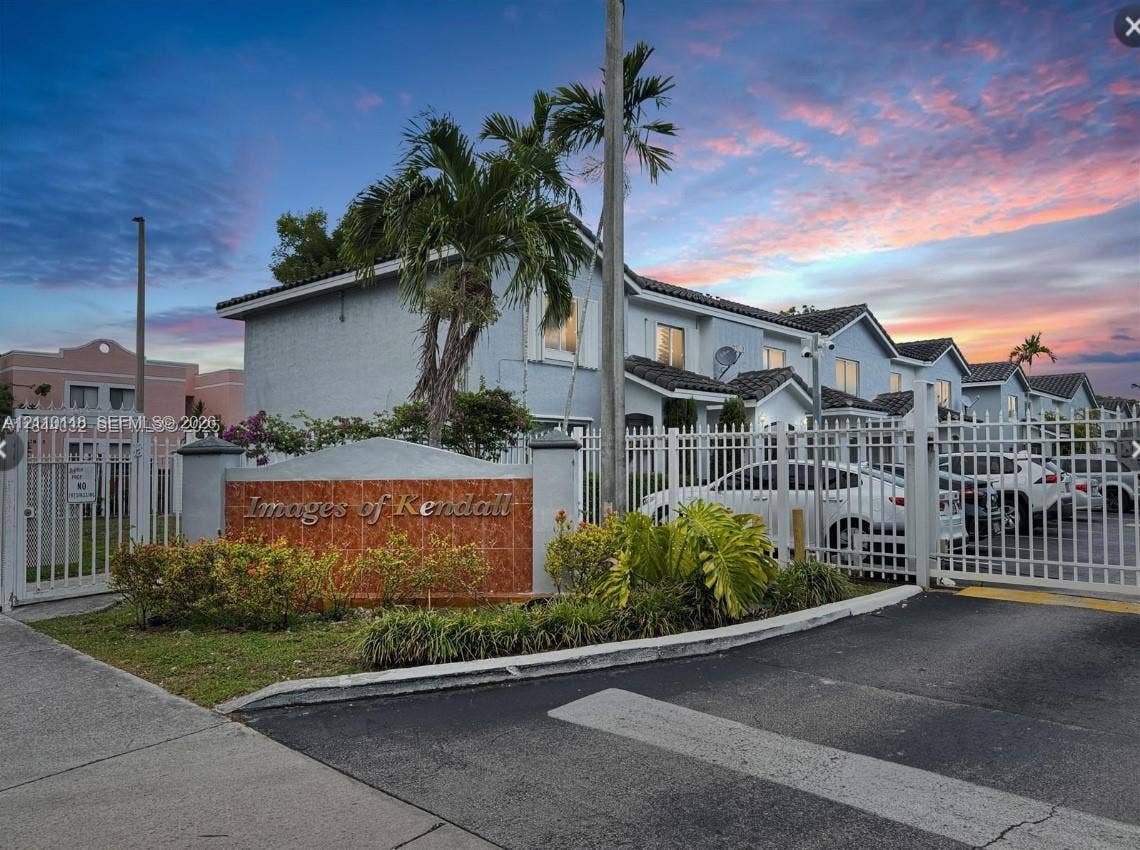 7991 SW 152nd Avenue, #701-7, Miami, Miami, FL 33193 Gated residential entrance featuring custom stone-inlay signage, perimeter fencing, paved driveway, and mature landscaping