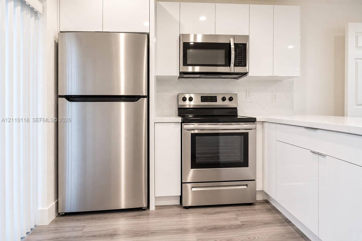 7991 SW 152nd Avenue, #701-7, Miami, Miami, FL 33193 Kitchen featuring high-gloss white cabinetry, stainless steel appliances, solid surface countertops, and wood-finish flooring