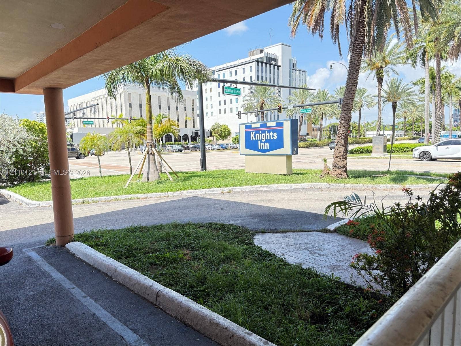 Exterior area featuring a paved parking surface, mature palm trees, and manicured landscaping