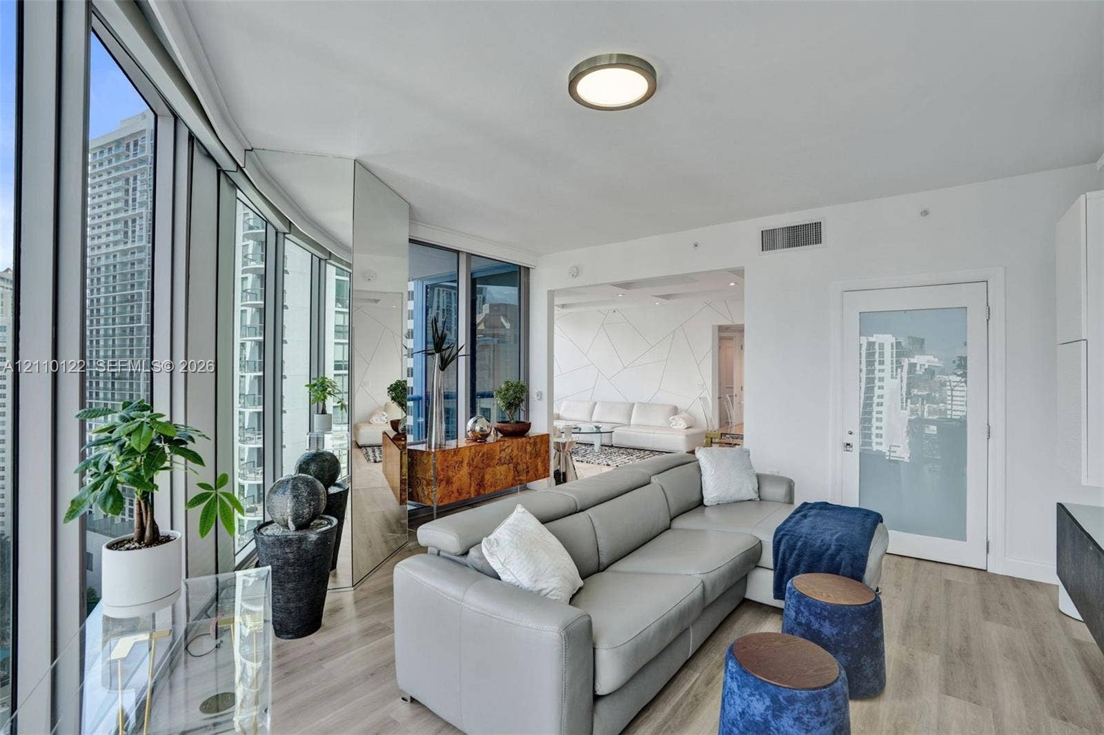 333 Las Olas Way, #2708, Fort Lauderdale, FL 33301 Floor-to-ceiling windows, wood-finish flooring, full-height mirrored wall panel, and a frosted glass-paneled interior door