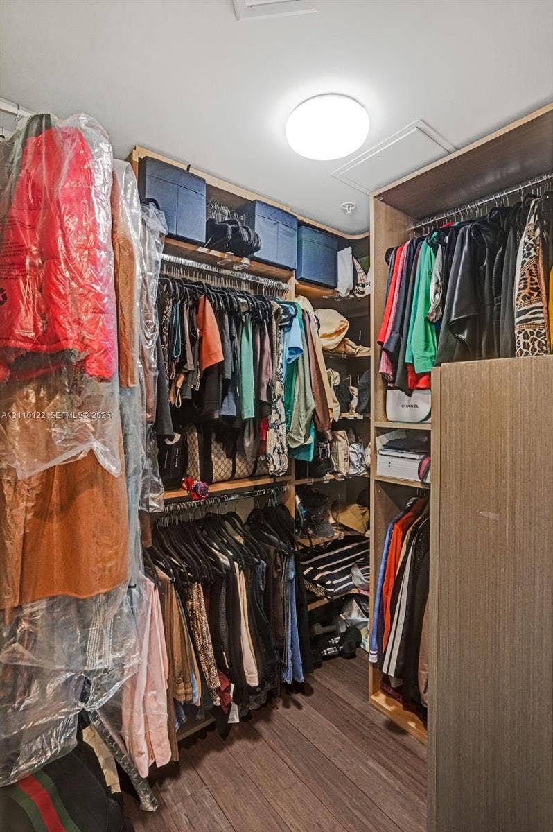 333 Las Olas Way, #2708, Fort Lauderdale, FL 33301 Custom walk-in closet featuring floor-to-ceiling wooden cabinetry, tiered hanging rods, integrated shelving units, and flush-mount overhead lighting