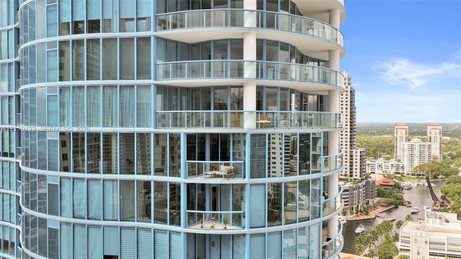 333 Las Olas Way, #2708, Fort Lauderdale, FL 33301 High-rise exterior featuring a rounded architectural facade, floor-to-ceiling glass windows, and multiple private balconies with glass railings