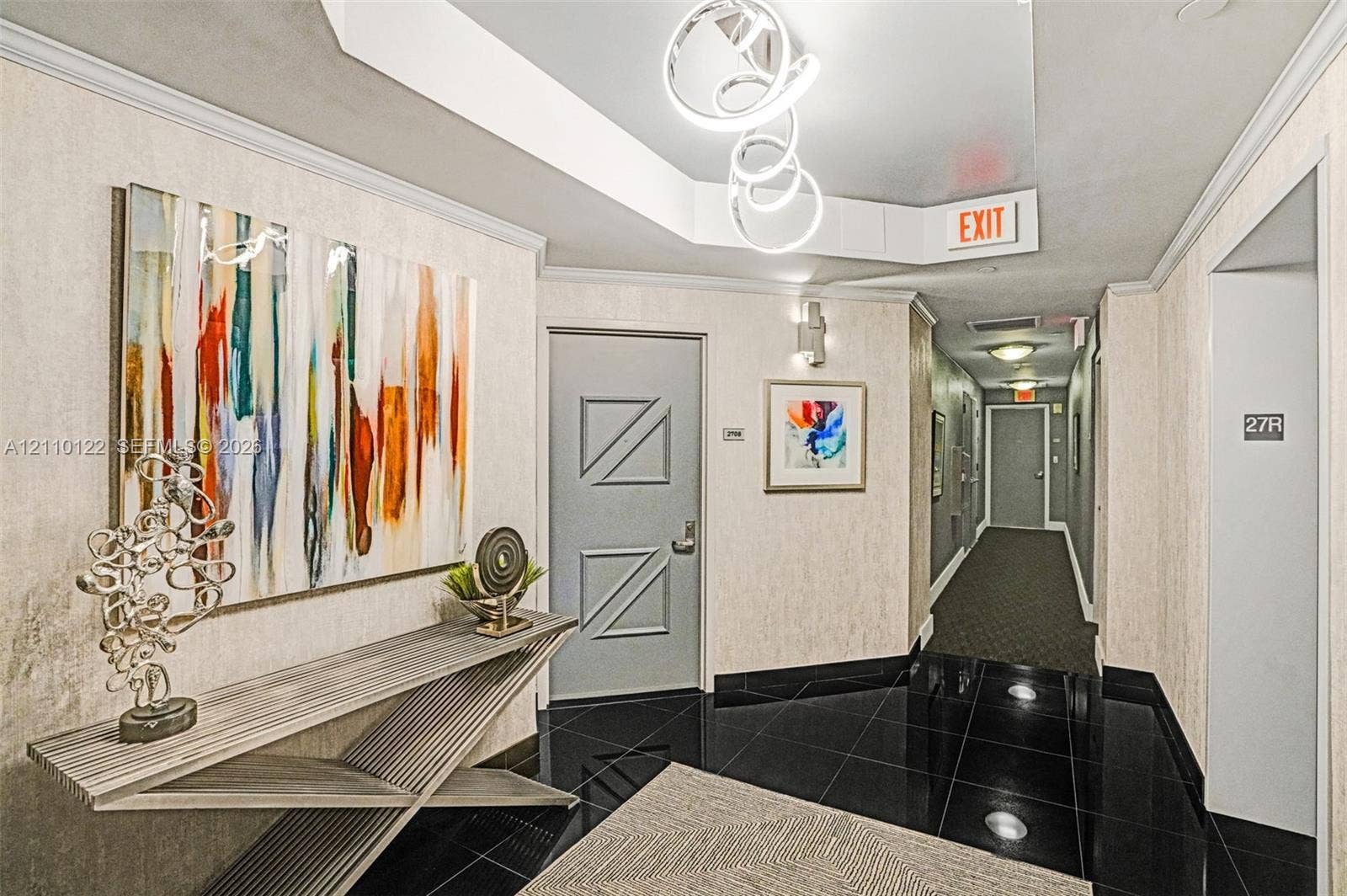 333 Las Olas Way, #2708, Fort Lauderdale, FL 33301 Foyer featuring black tiled flooring, a recessed tray ceiling with sculptural pendant lighting, and textured wall coverings