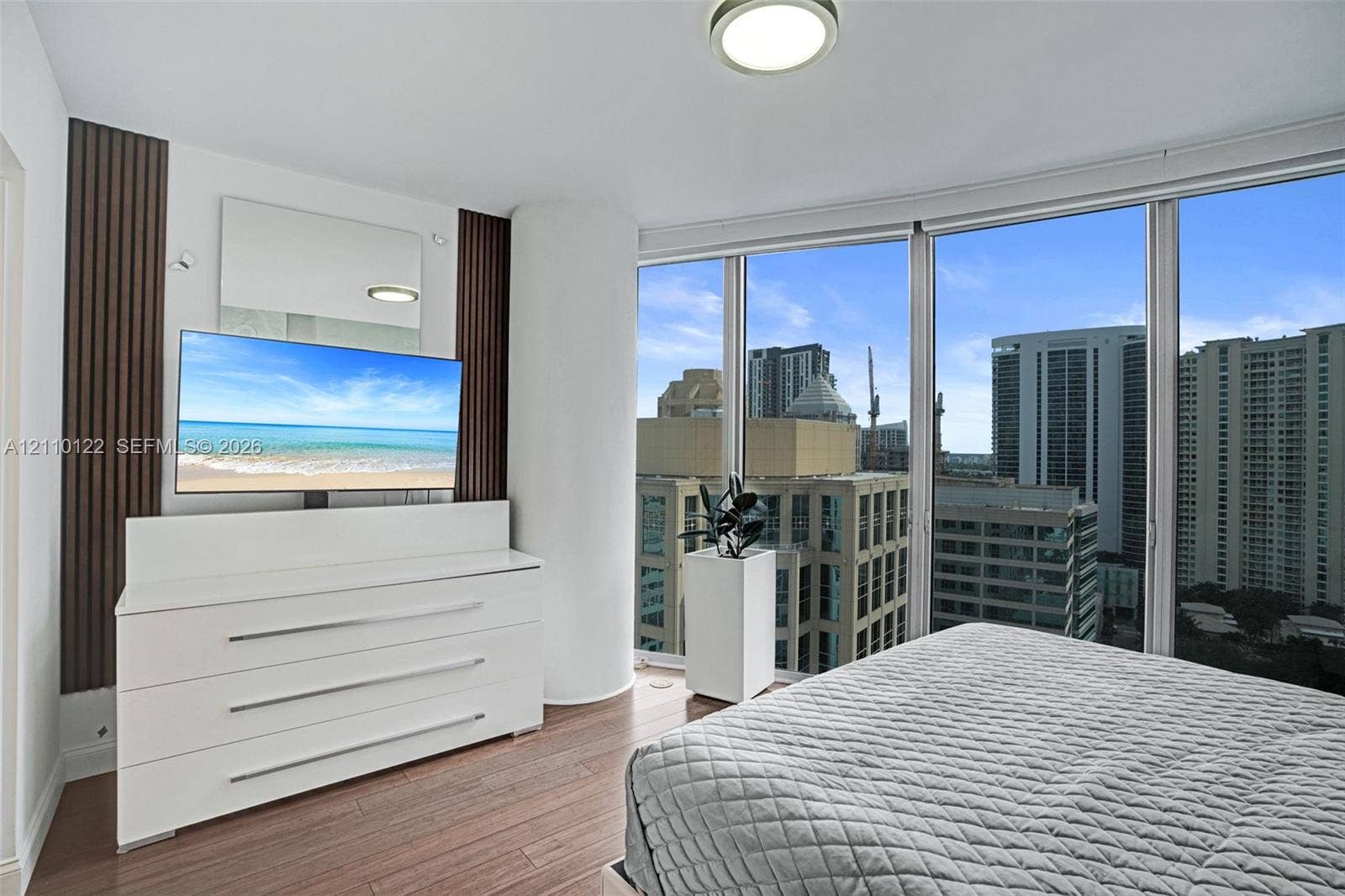 333 Las Olas Way, #2708, Fort Lauderdale, FL 33301 Floor-to-ceiling windows featuring urban scenery, wood-finish flooring, and decorative vertical wall paneling