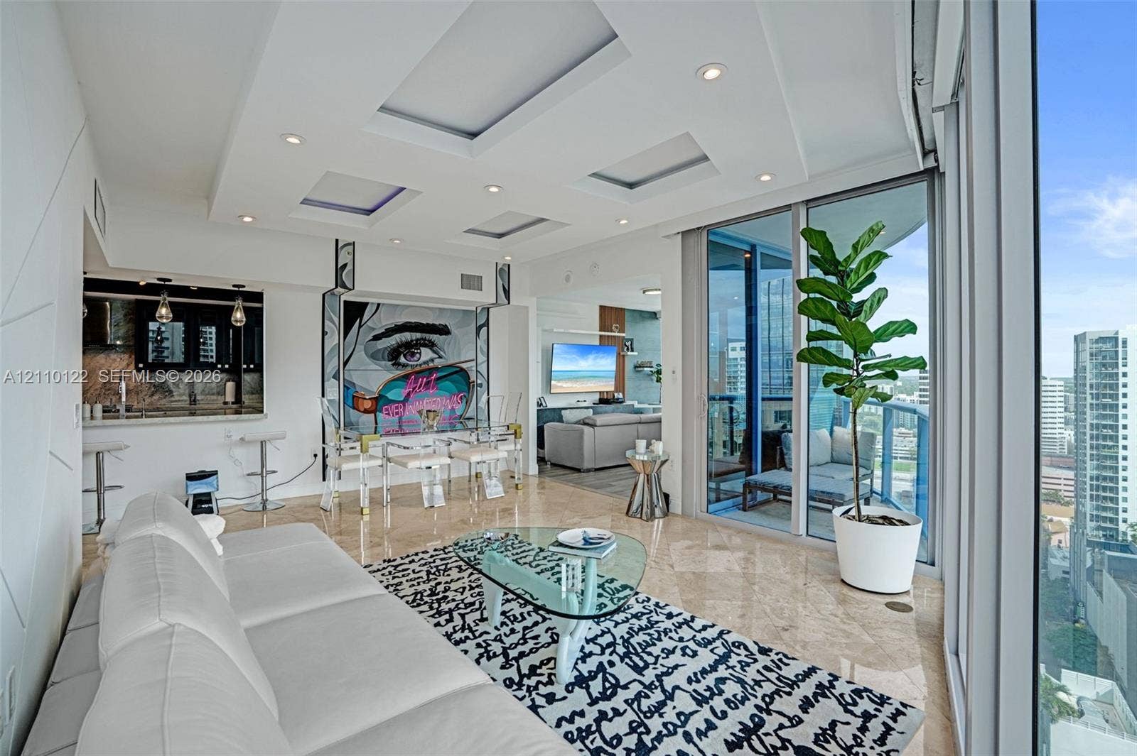 333 Las Olas Way, #2708, Fort Lauderdale, FL 33301 Living area featuring floor-to-ceiling glass sliding doors, tray ceiling with recessed lighting, polished stone flooring, and a kitchen pass-through window with an integrated breakfast bar