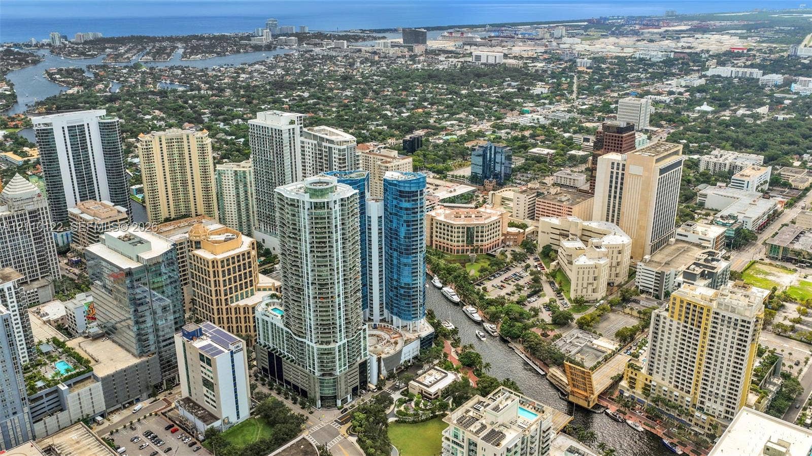 333 Las Olas Way, #2708, Fort Lauderdale, FL 33301 Aerial perspective of high-rise structures featuring glass curtain walls, balconies, integrated parking facilities, and immediate proximity to urban waterways