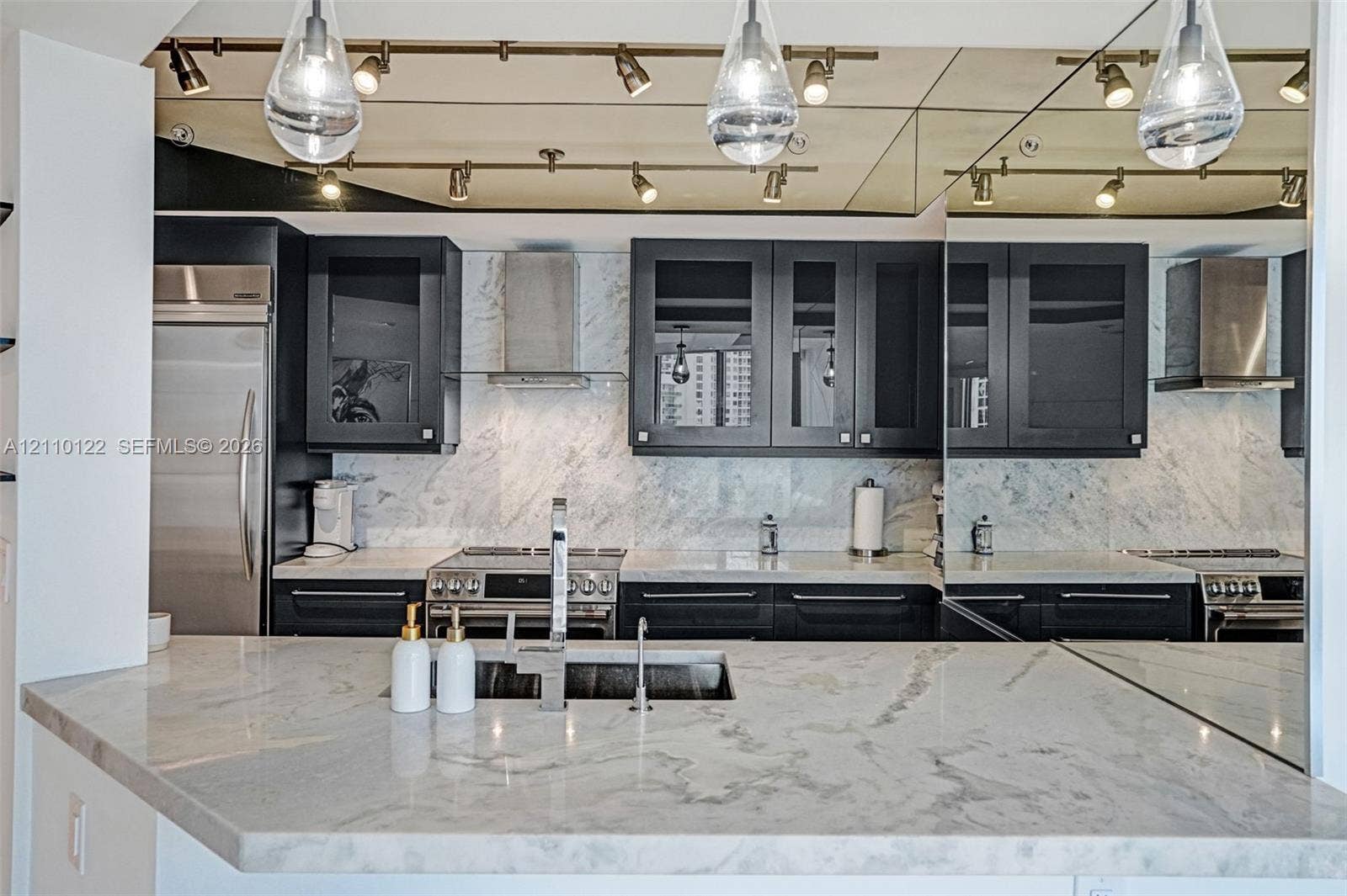 333 Las Olas Way, #2708, Fort Lauderdale, FL 33301 Kitchen featuring dark cabinetry, stone countertops, stone tile backsplash, stainless steel appliances, and mounted track lighting
