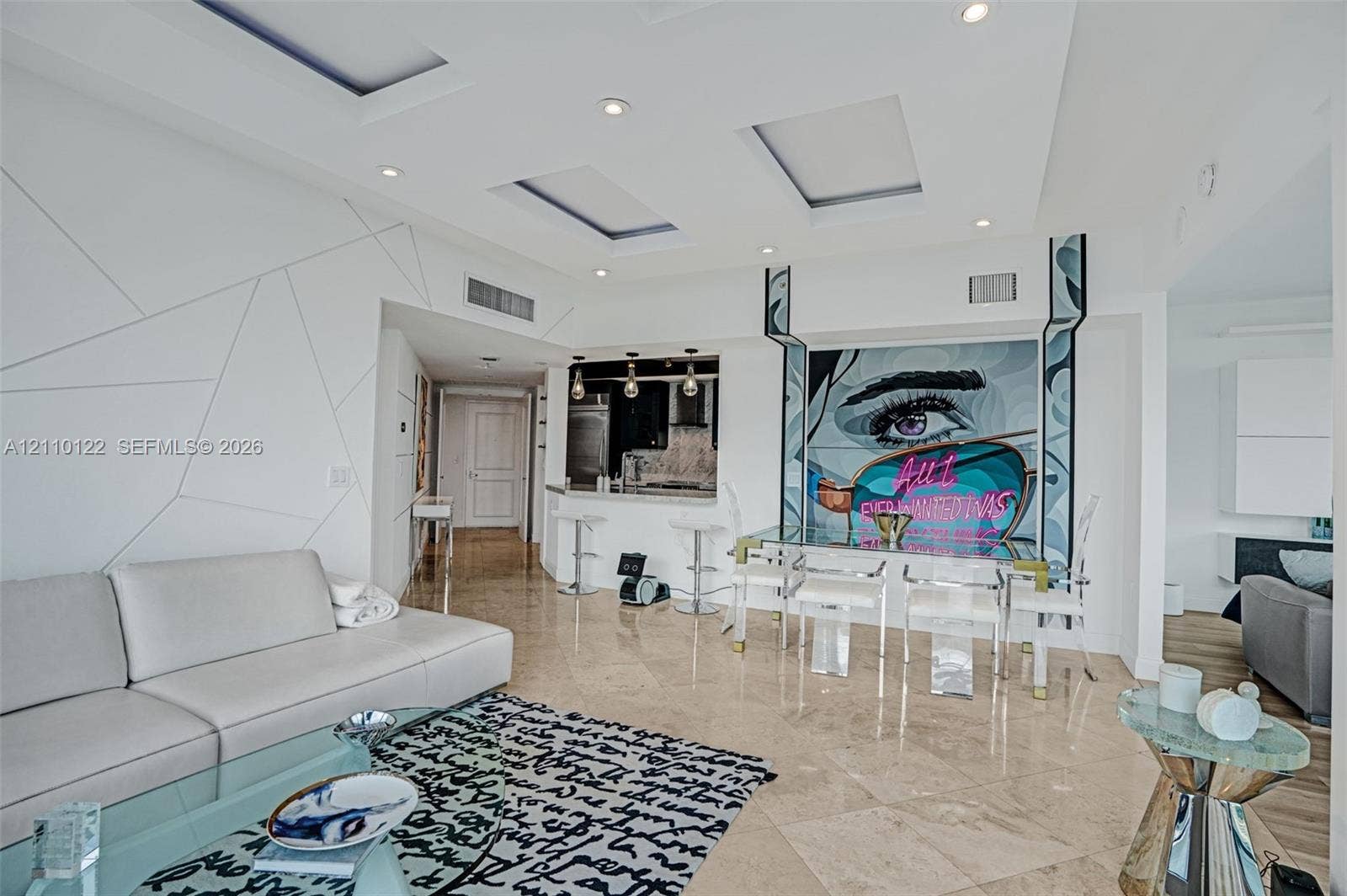 333 Las Olas Way, #2708, Fort Lauderdale, FL 33301 Open-concept living space featuring stone-finish flooring, recessed ceiling lighting with geometric coffers, a pass-through kitchen bar, and a wall accent with integrated lighting