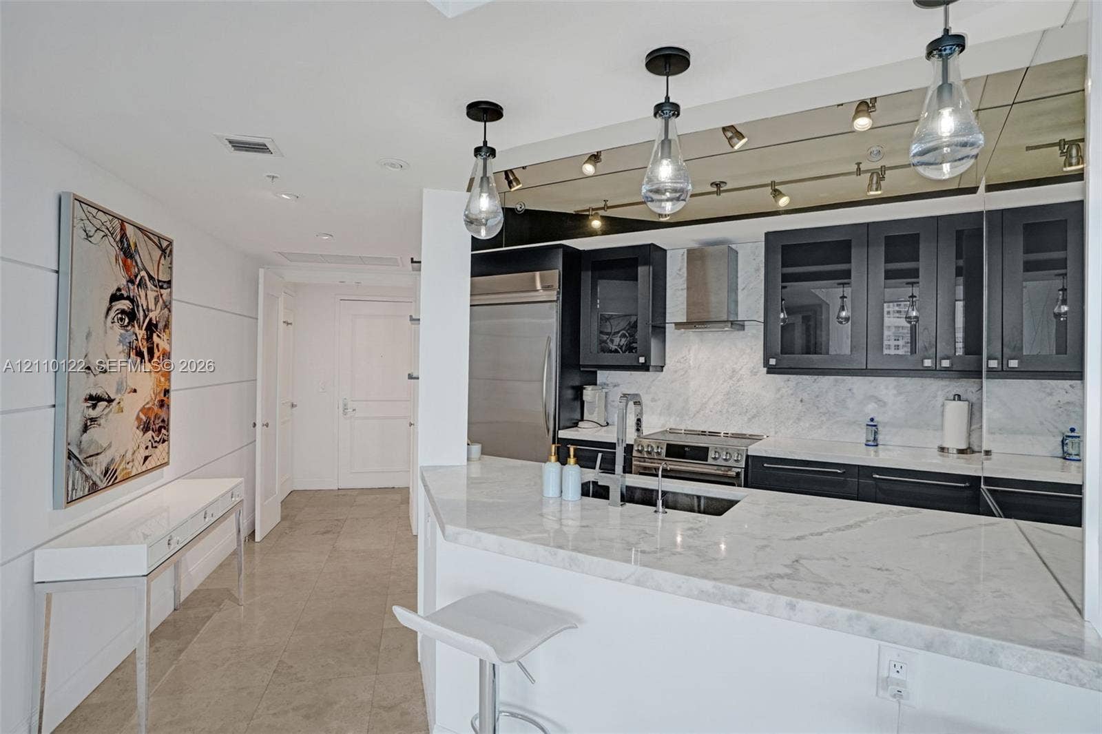333 Las Olas Way, #2708, Fort Lauderdale, FL 33301 Kitchen featuring stone countertops, dark-finished cabinetry with glass-panel inserts, stainless steel appliances, and teardrop pendant lighting