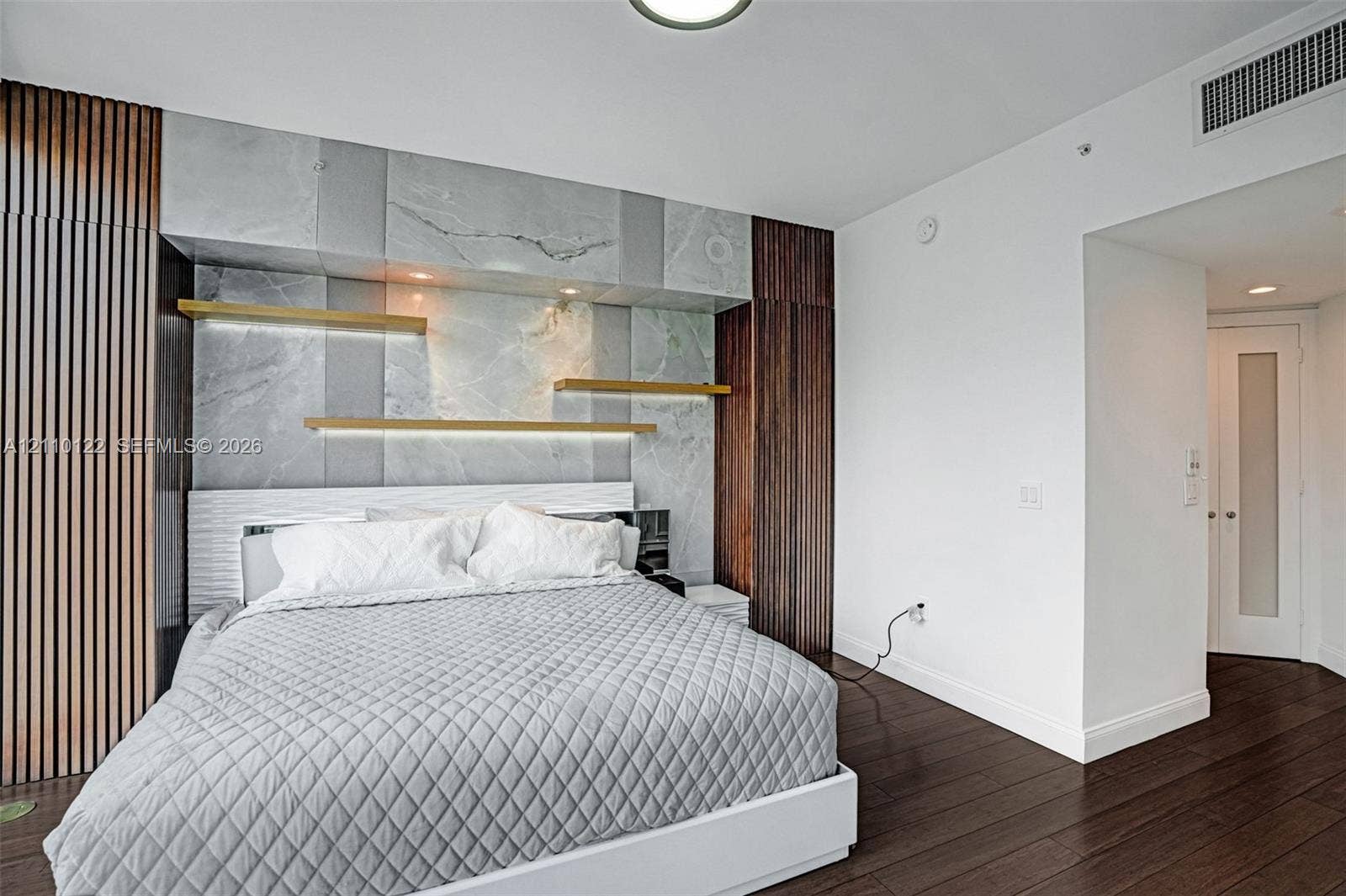 333 Las Olas Way, #2708, Fort Lauderdale, FL 33301 Floor-to-ceiling wood-slat paneling, stone wall feature, integrated display shelving with recessed lighting, and wood-finish flooring