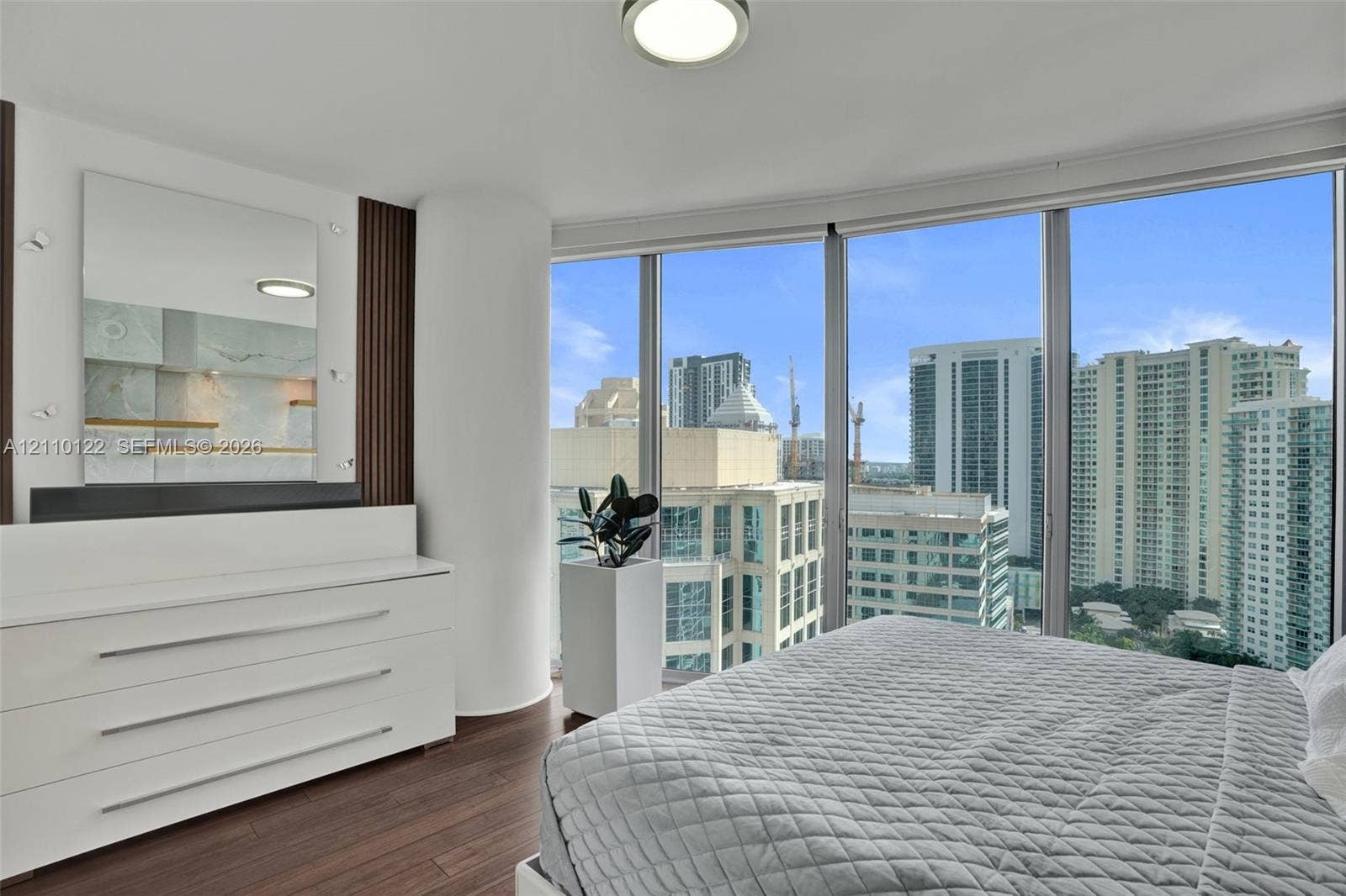 333 Las Olas Way, #2708, Fort Lauderdale, FL 33301 Floor-to-ceiling windows, dark wood-finish flooring, built-in wall-mounted mirror, and vertical slat accent paneling