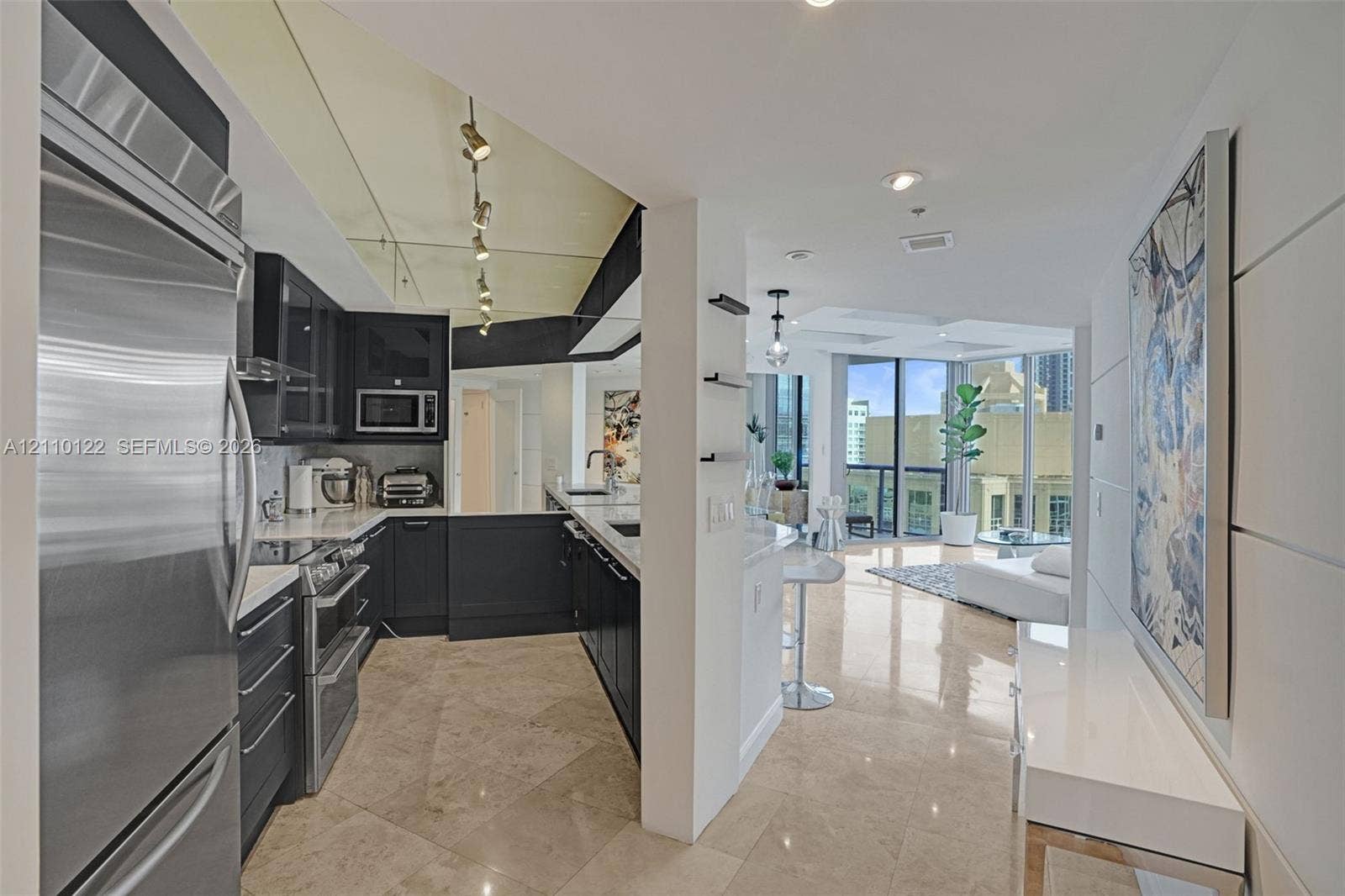 333 Las Olas Way, #2708, Fort Lauderdale, FL 33301 Kitchen featuring dark cabinetry, stainless steel appliances, and large-format tile flooring, complemented by recessed lighting and a mirrored ceiling accent