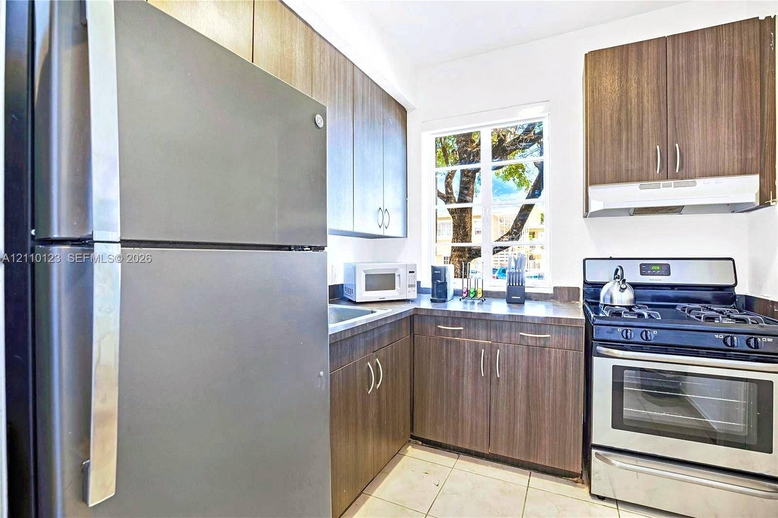 301 86th Street, #303-3, Miami Beach, Miami Beach, FL 33141 Kitchen featuring wood-finish cabinetry, stainless steel appliances, dark countertops, and tile flooring