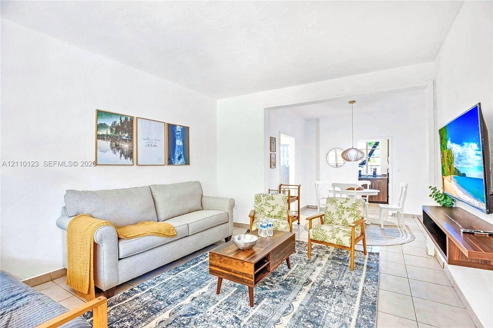 301 86th Street, #303-3, Miami Beach, Miami Beach, FL 33141 Open-concept interior featuring neutral wall finishes, ceramic tile flooring, a wall-mounted wooden media shelf, and a contemporary pendant light fixture