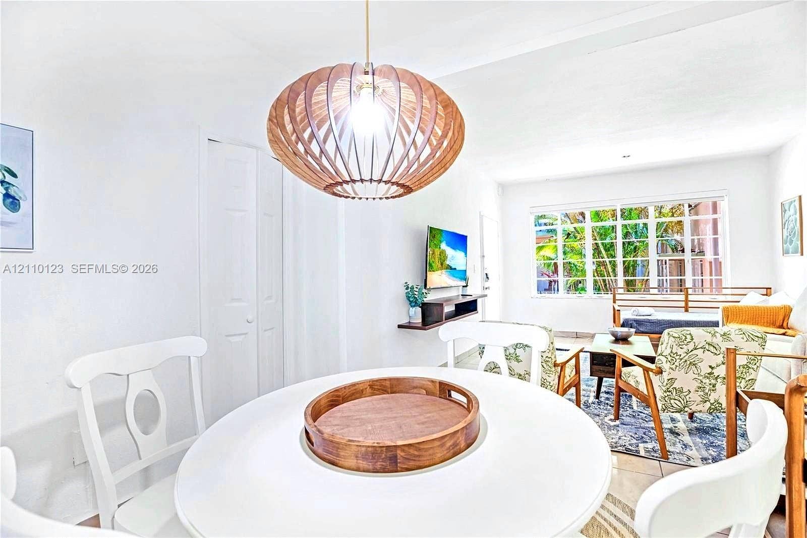301 86th Street, #303-3, Miami Beach, Miami Beach, FL 33141 Sculptural wood-slat pendant light fixture, grid-pane windows with outdoor greenery, and light-toned tile flooring