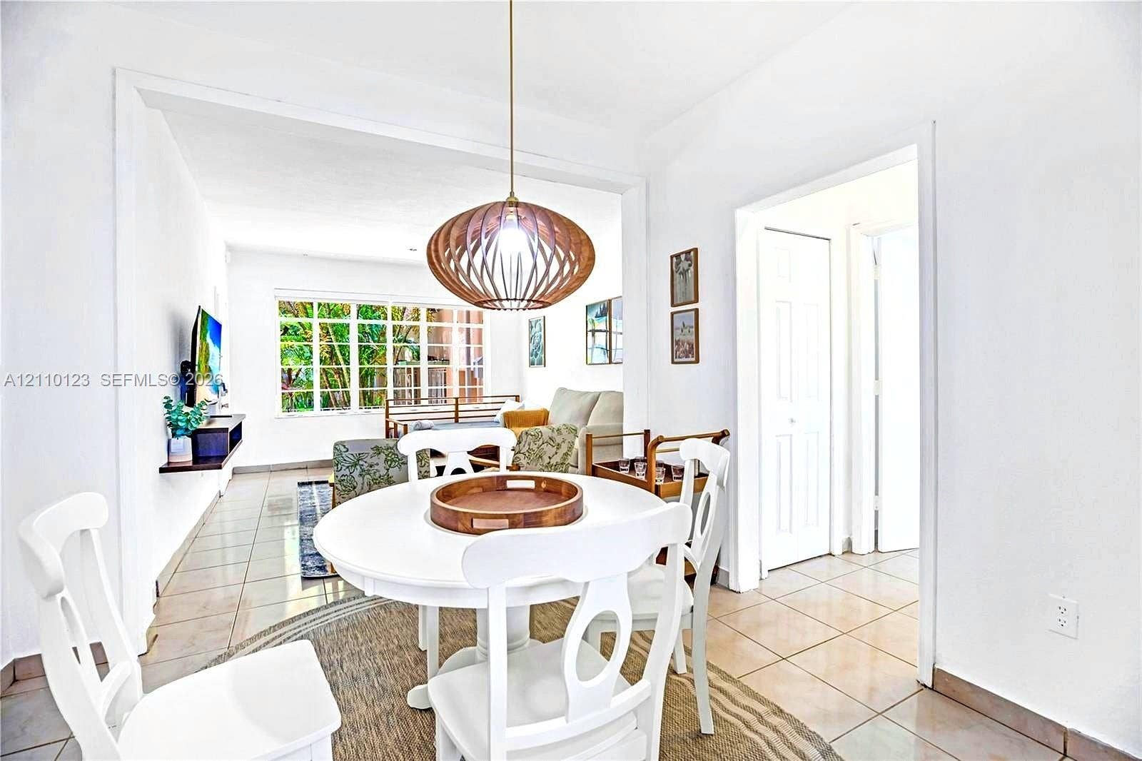 301 86th Street, #303-3, Miami Beach, Miami Beach, FL 33141 Dining area featuring large-format ceramic tile flooring, a geometric lattice-style pendant light fixture, and a floating wall-mounted shelf