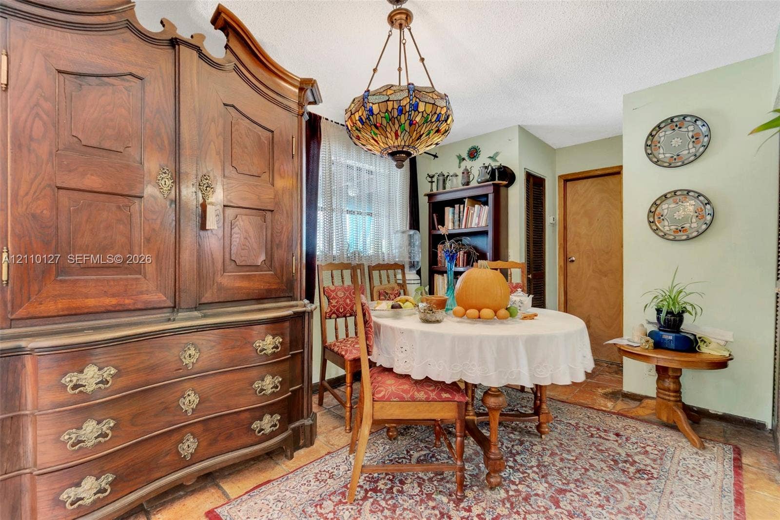 10164 SW 52nd Street, Cooper City, FL 33328 Stained-glass chandelier with intricate metal detailing, wood-finish tile flooring, and built-in wood shelving unit