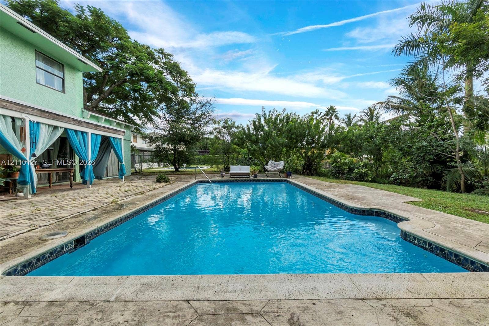 10164 SW 52nd Street, Cooper City, FL 33328 In-ground swimming pool featuring a concrete deck, covered patio, and established landscaping