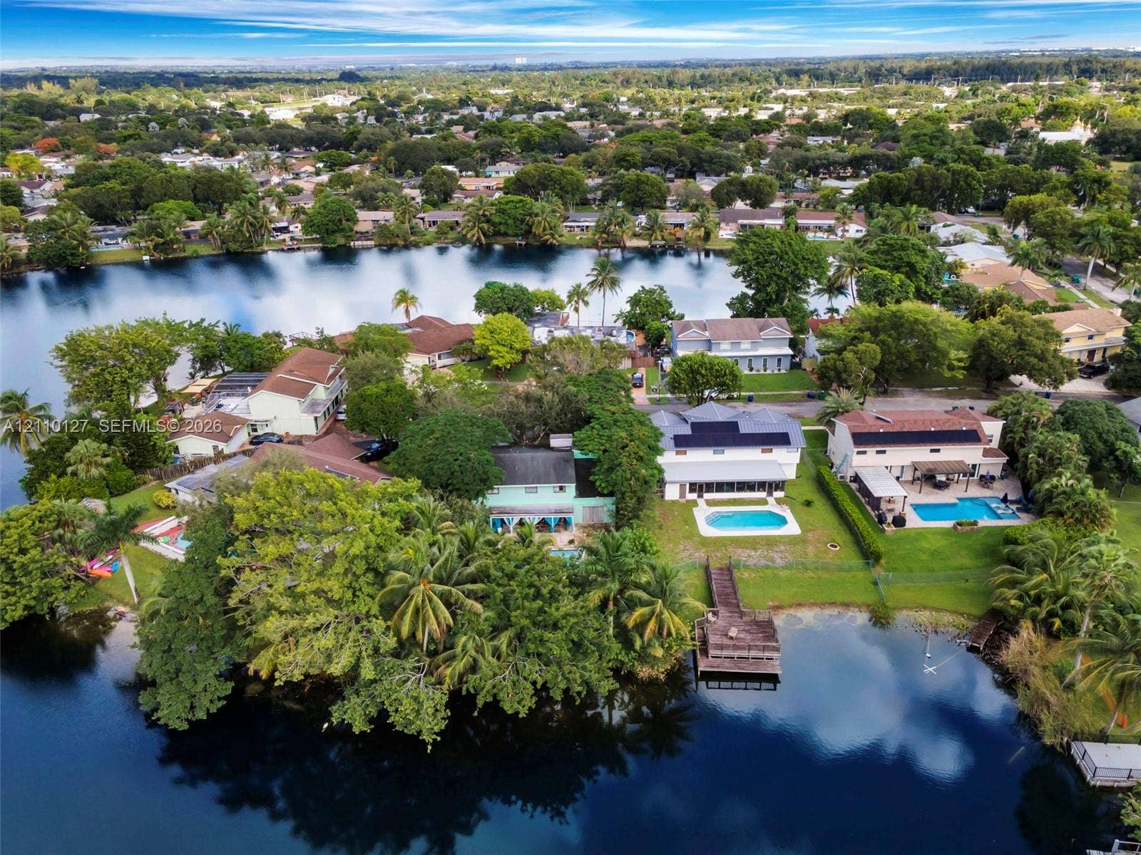 10164 SW 52nd Street, Cooper City, FL 33328 Waterfront residential setting featuring a private dock, swimming pools, mature landscaping, and solar panel arrays