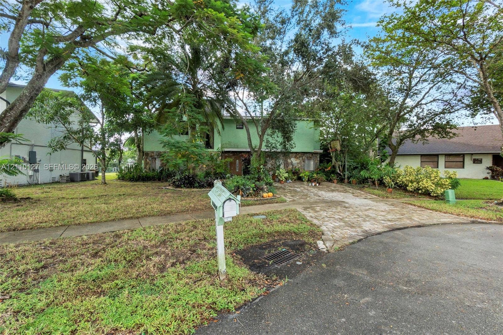 10164 SW 52nd Street, Cooper City, FL 33328 Exterior facade featuring stone veneer detailing, multi-level architectural design, paved driveway, and mature landscaping