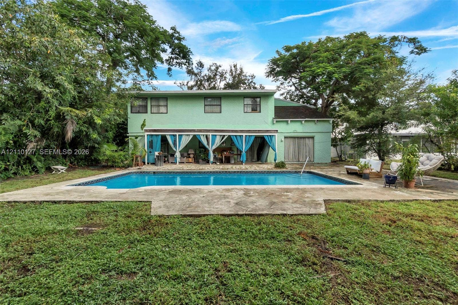 10164 SW 52nd Street, Cooper City, FL 33328 Two-story residence featuring a covered patio, swimming pool with concrete decking, and mature trees on the property grounds