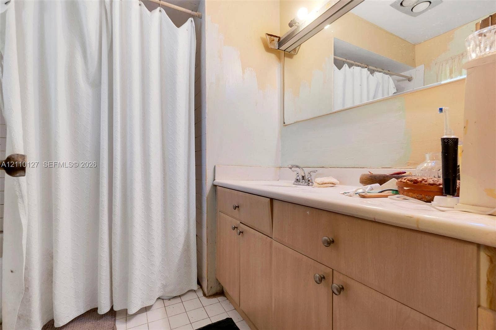 10164 SW 52nd Street, Cooper City, FL 33328 Bathroom featuring a vanity with light-tone wood-finish cabinetry, a solid-surface countertop with an integrated sink, a large wall-mounted mirror, and a shower area with a curtain rod