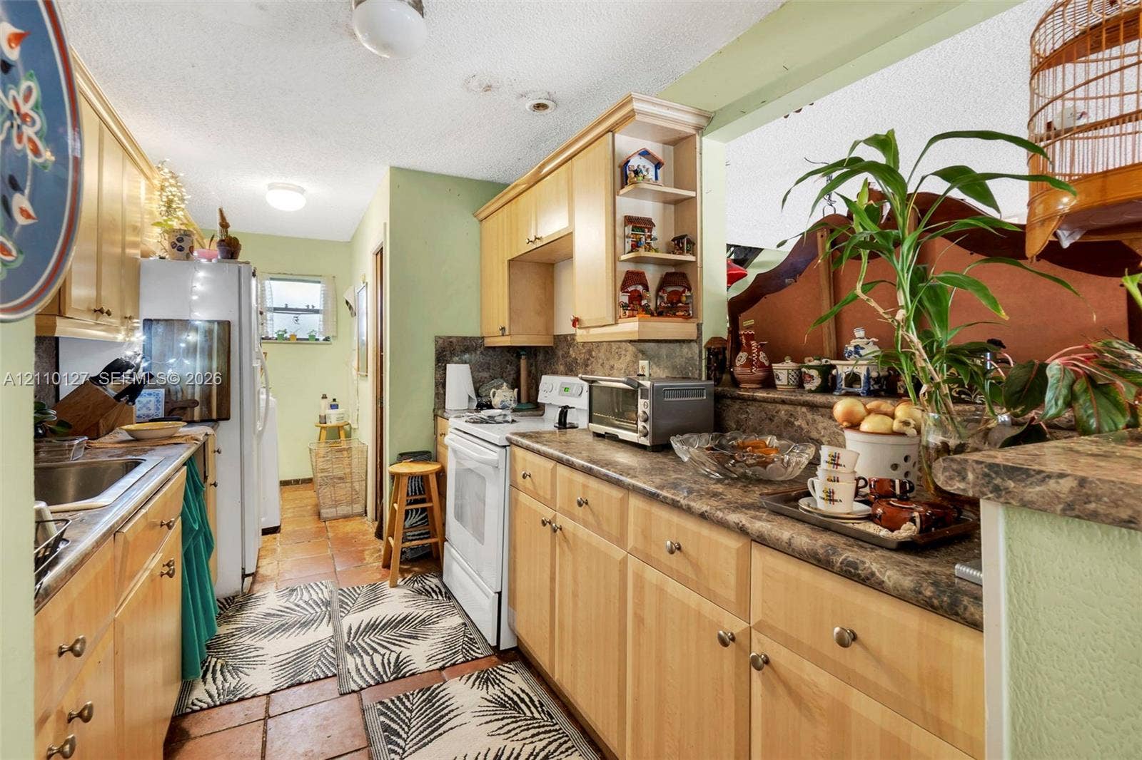 10164 SW 52nd Street, Cooper City, FL 33328 Kitchen featuring light-finish wood cabinetry, laminate countertops with a stone-pattern finish, ceramic tile flooring, and integrated open corner shelving