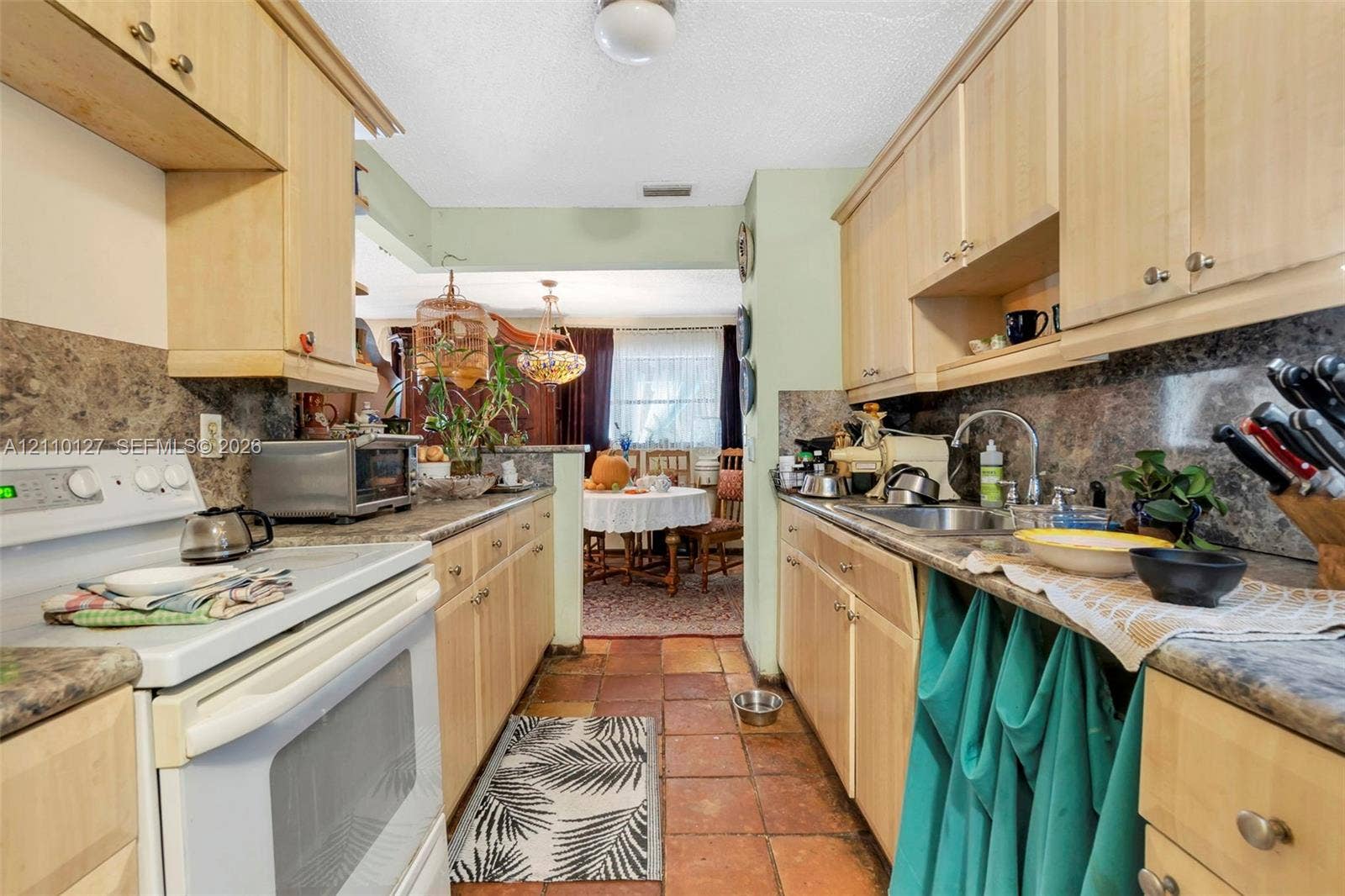 10164 SW 52nd Street, Cooper City, FL 33328 Kitchen featuring light-finish cabinetry, stone-patterned laminate countertops, tile flooring, and a stainless steel undermount sink