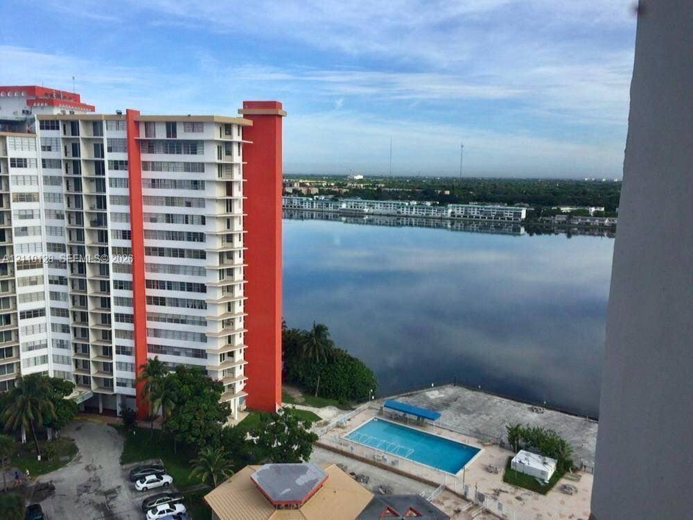 1351 NE Miami Gardens Drive, #1624E, Miami, FL 33179 High-rise building exterior featuring a rectangular outdoor swimming pool, paved pool deck, and direct waterfront placement