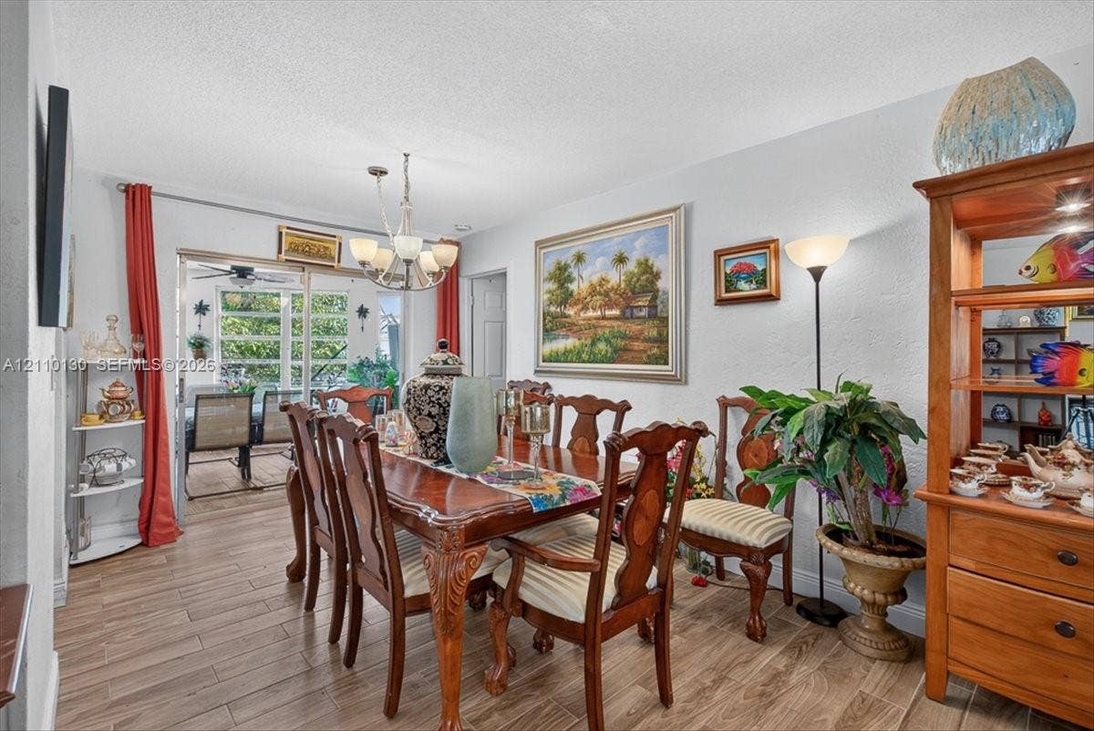 Dining area featuring wood-finish tile flooring, multi-arm chandelier, and sliding glass door
